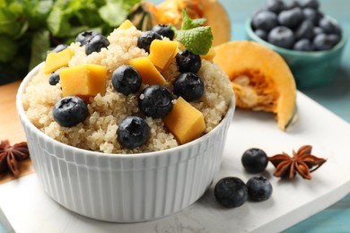 Tasty quinoa porridge with blueberries and pumpkin in bowl on table, closeup