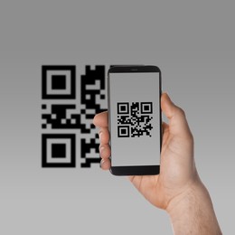 Man scanning QR code with smartphone on light grey background, closeup