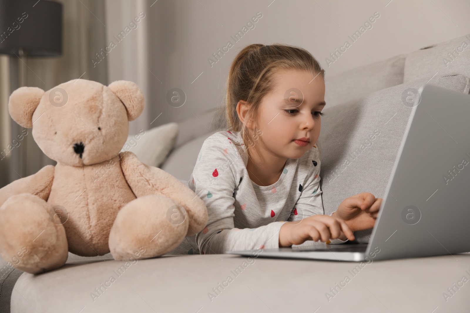 Photo of Little girl learning English indoors at online lesson