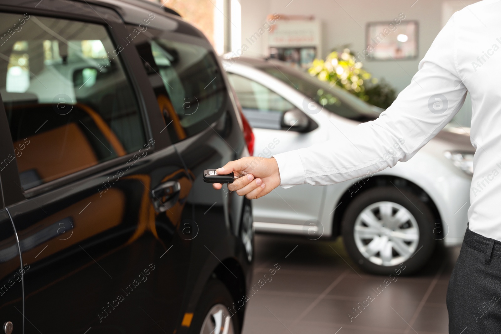 Photo of Young man turning off alarm system with car key indoors, closeup