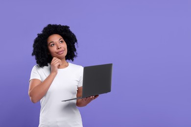 Beautiful young woman with laptop on purple background. Space for text