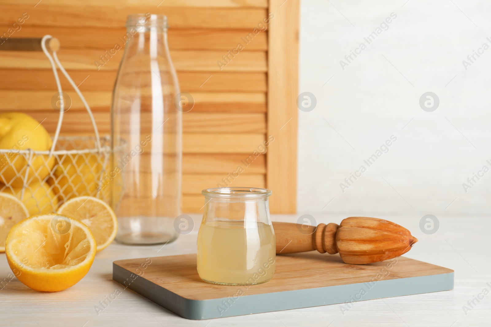 Photo of Composition with freshly squeezed lemon juice in glass jar on table. Space for text
