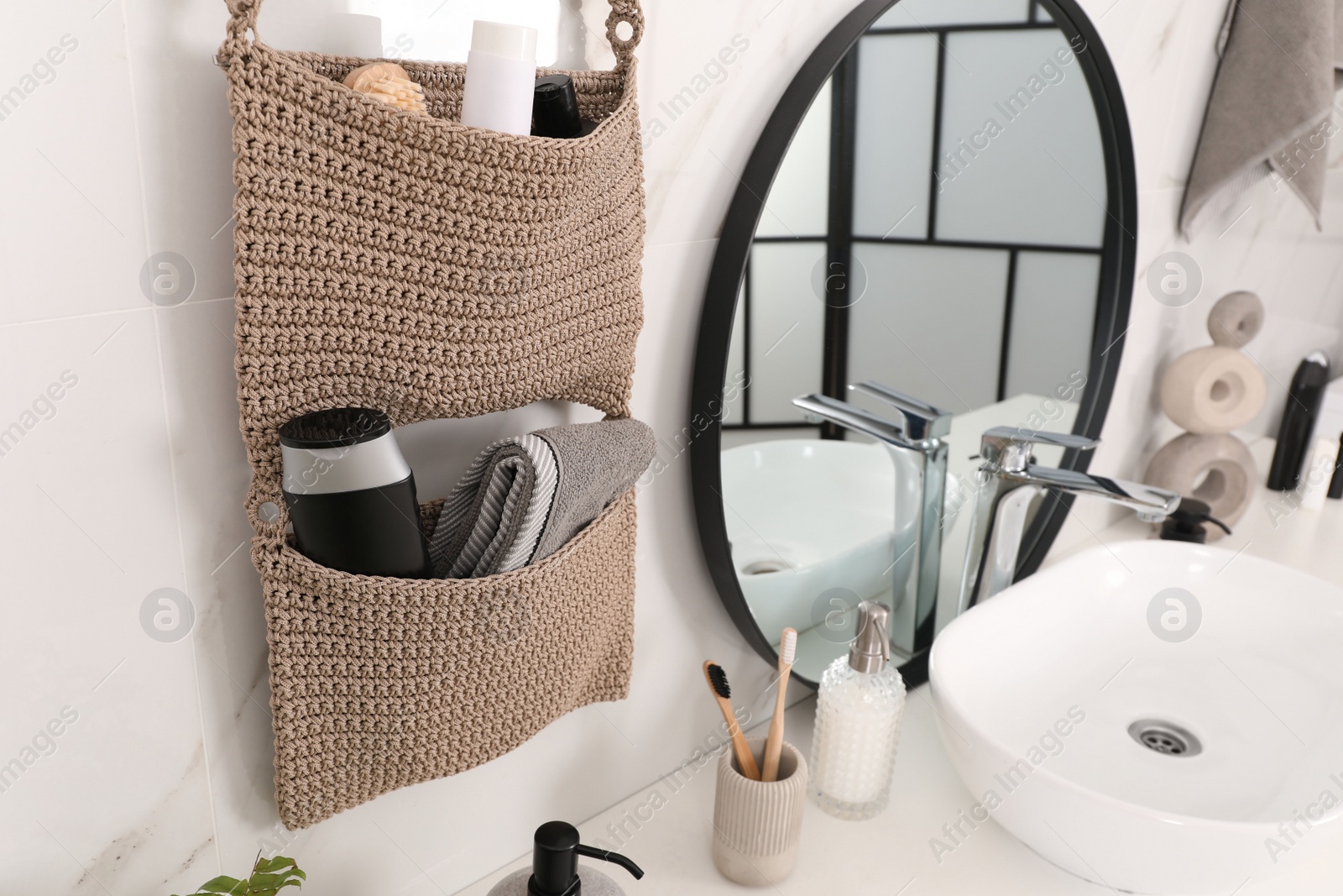 Photo of Knitted organizer hanging on wall in bathroom