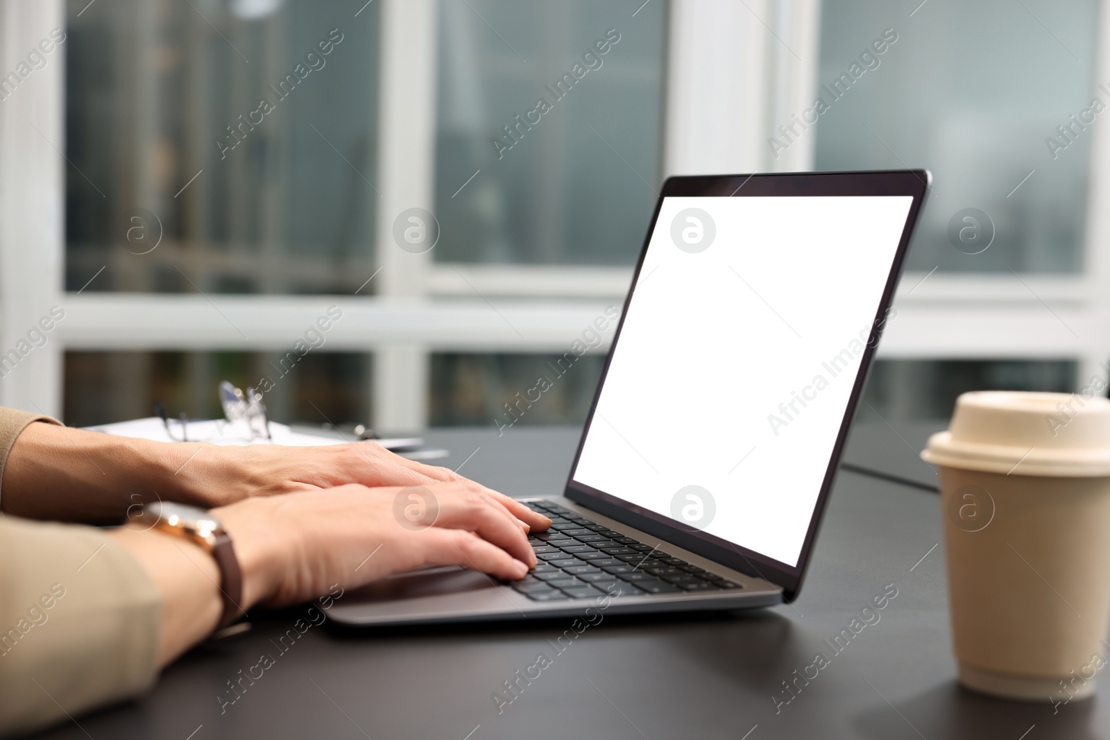 Photo of Woman working on laptop at black desk in office, closeup