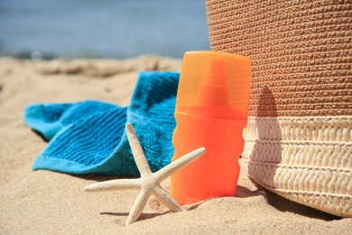Sunscreen, starfish, bag and towel on beach. Sun protection care