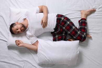 Man suffering from insomnia on bed, top view