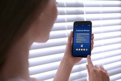 Woman using smartphone to give feedback indoors, closeup. Customer review