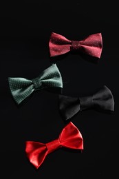 Photo of Stylish color bow ties on black background, above view