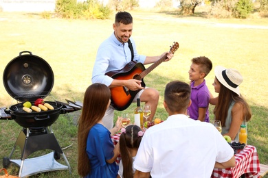 Man playing guitar for friends at picnic in park