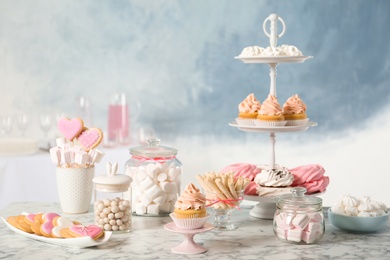 Candy bar with different sweets on white marble table against color background