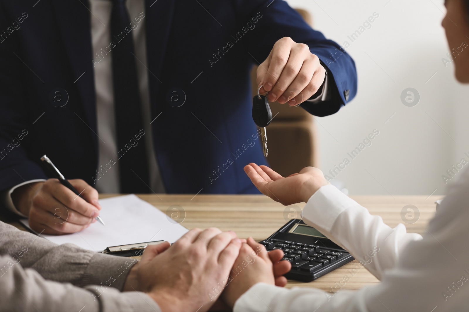 Photo of Salesman giving key to customers in office, closeup. Buying new car