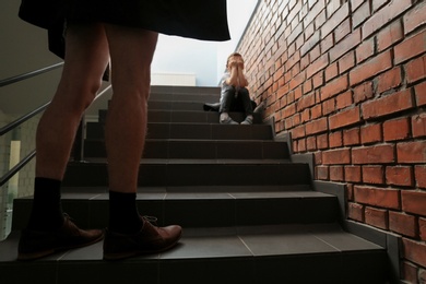 Male exhibitionist opening his coat in front of scared little boy indoors. Child in danger