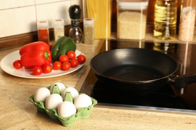 Photo of Many fresh eggs and vegetables near frying pan on wooden countertop in kitchen