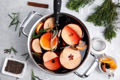 Photo of Tasty mulled wine with spices on grey marble table, flat lay