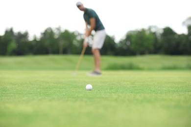 Photo of Man playing golf on green course, ball in focus. Sport and leisure