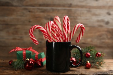 Photo of Many sweet candy canes, gift boxes  and Christmas decor on wooden table