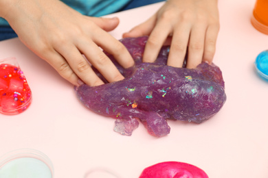 Photo of Child playing with purple slime at table, closeup