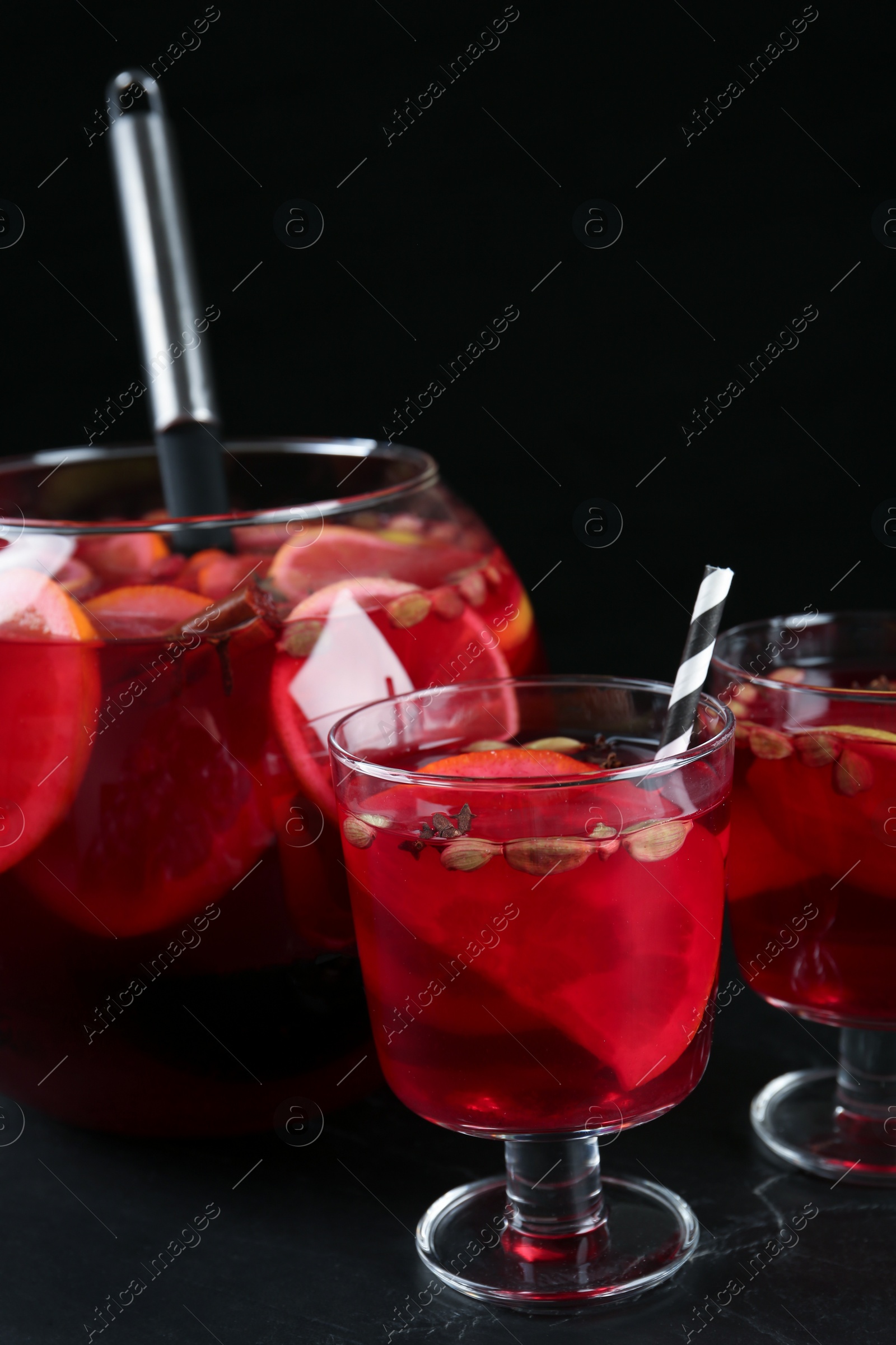 Photo of Aromatic punch drink on dark table against black background