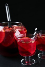 Photo of Aromatic punch drink on dark table against black background