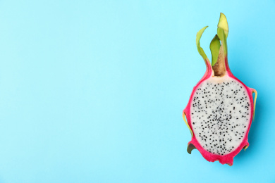 Photo of Half of delicious ripe dragon fruit (pitahaya) on light blue background, top view. Space for text
