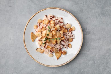 Plate with baked salsify roots, lemon and rice on light grey table, top view