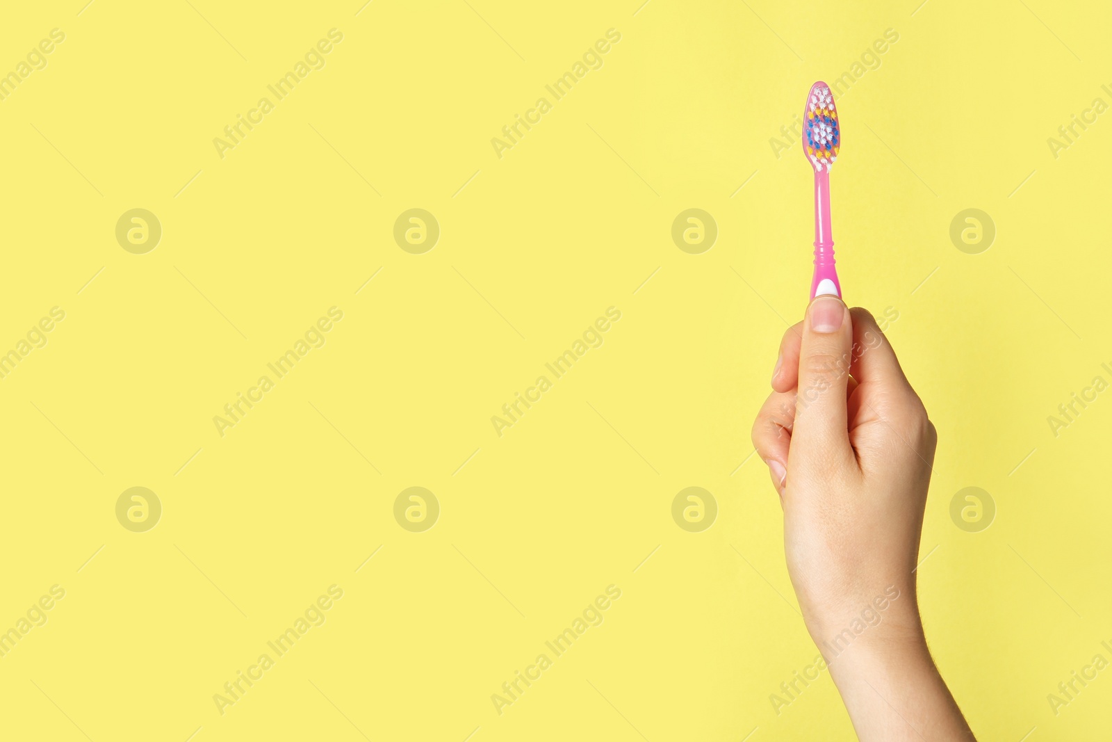 Photo of Woman holding manual toothbrush against color background