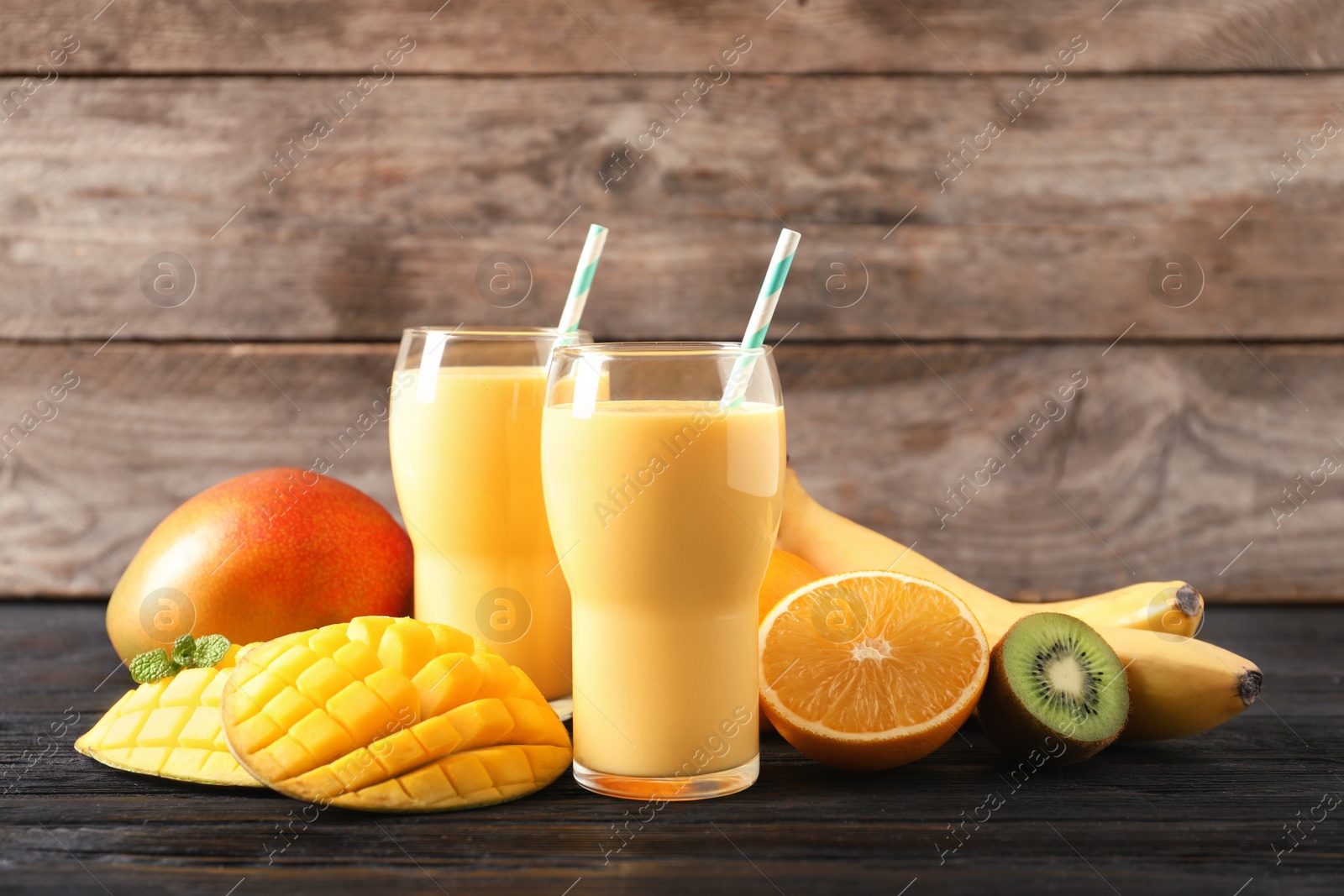 Photo of Tasty tropical drink with mango and fresh fruits on wooden table