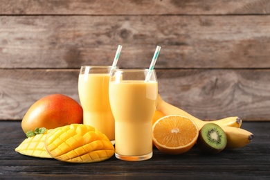 Photo of Tasty tropical drink with mango and fresh fruits on wooden table