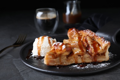 Photo of Slice of traditional apple pie with ice cream served on grey table, closeup