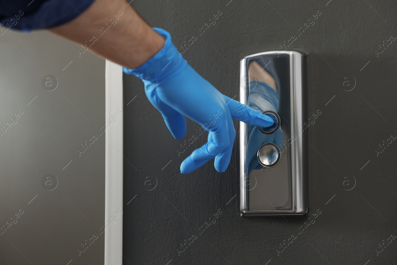 Photo of Man in glove pressing elevator call button, closeup. Protective measure