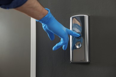 Photo of Man in glove pressing elevator call button, closeup. Protective measure