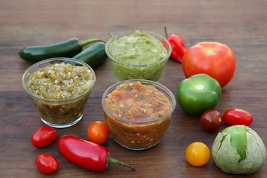 Tasty salsa sauces and ingredients on wooden table