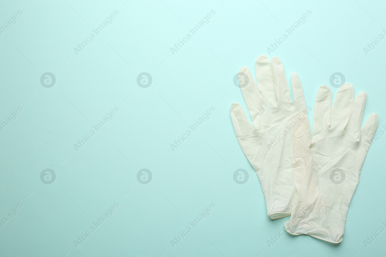 Photo of Pair of medical gloves on light blue background, flat lay. Space for text