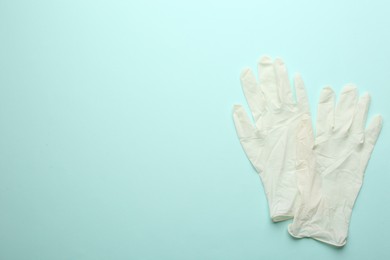 Photo of Pair of medical gloves on light blue background, flat lay. Space for text