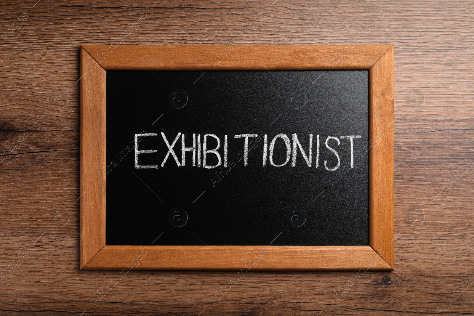 Photo of Blackboard with word Exhibitionist on wooden table, top view