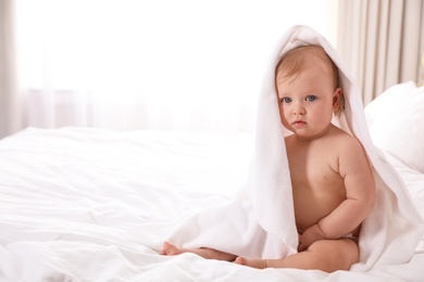 Cute little baby with soft towel on bed after bath. Space for text