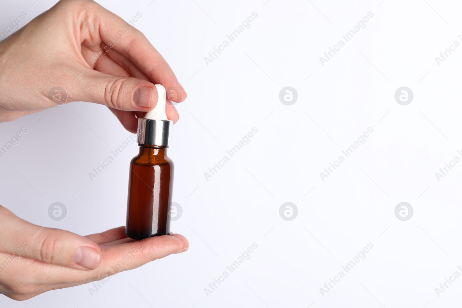 Photo of Woman with bottle of cosmetic serum on white background, closeup. Space for text