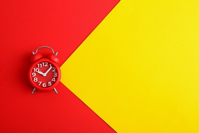 Modern alarm clock on color background, top view. Space for text