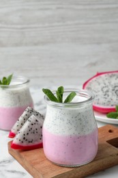 Photo of Delicious pitahaya smoothie, fruits and fresh mint on white marble table