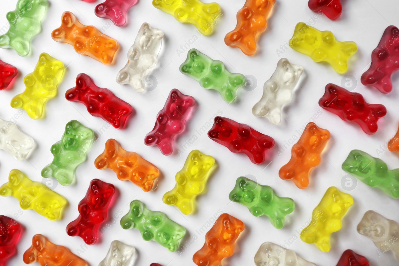 Photo of Many delicious little jelly bears on white background, top view