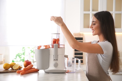 Young woman making tasty fresh juice at table in kitchen