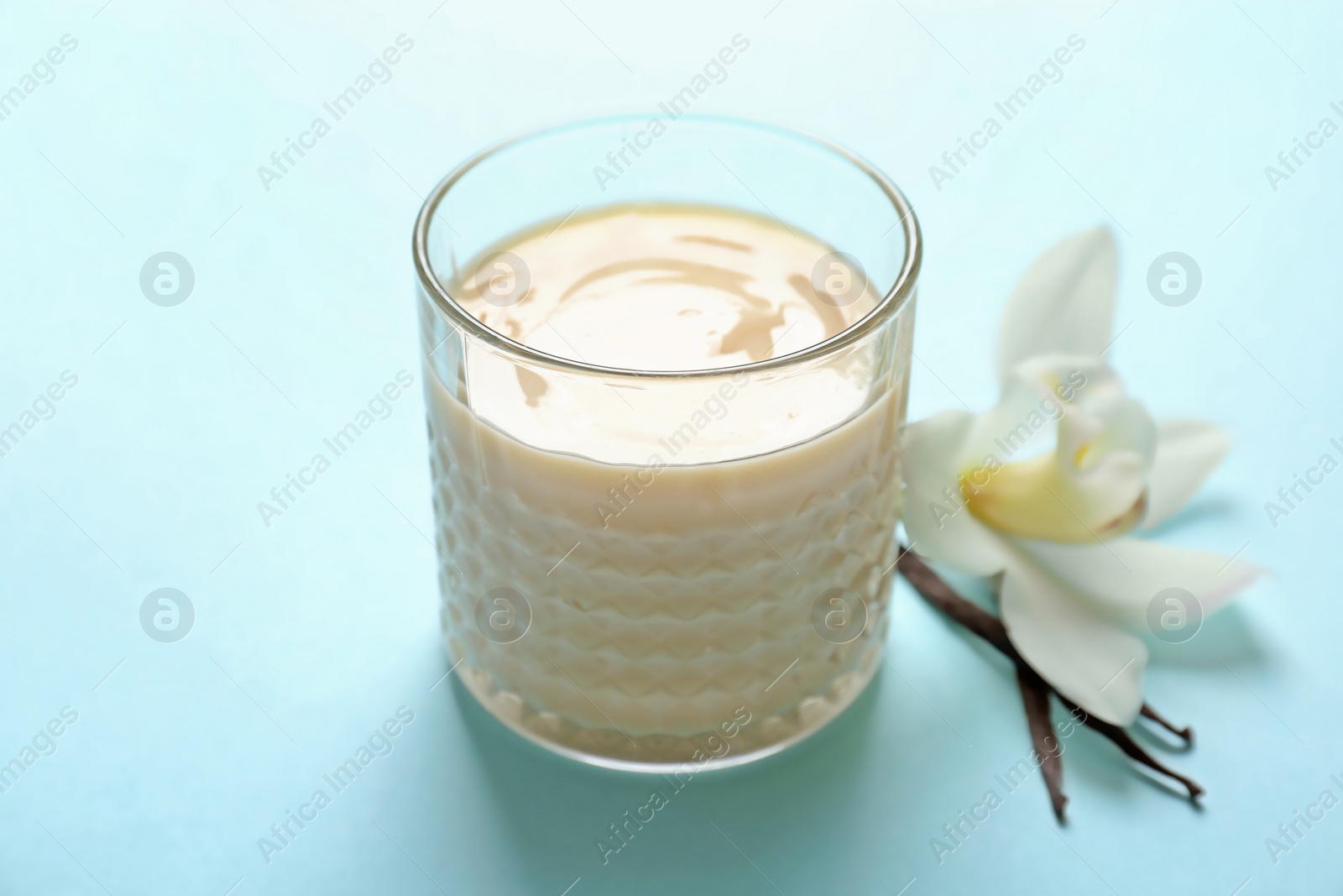 Photo of Vanilla pudding, sticks and flower on color background