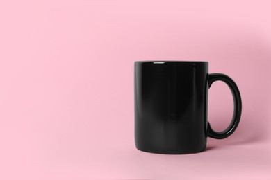 Photo of One black ceramic mug on pink background. Space for text