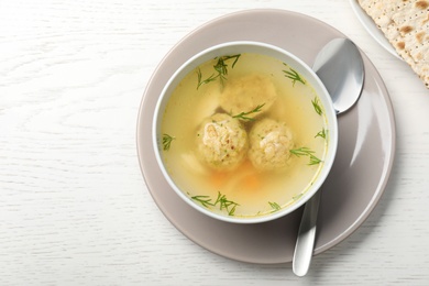 Flat lay composition with Jewish matzoh balls soup on white wooden table. Space for text