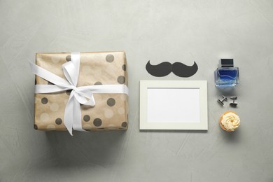 Photo of Empty photo frame, gift box and men accessories on grey table, flat lay with space for text. Father's day celebration