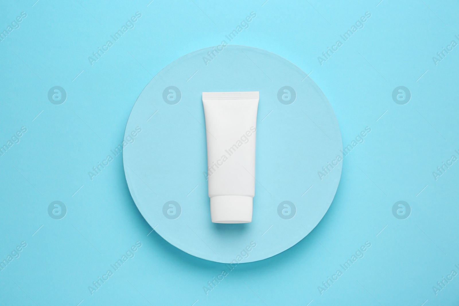 Photo of Tube of hand cream on turquoise background, top view