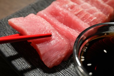 Photo of Taking tasty sashimi (pieces of fresh raw tuna) from plate, closeup