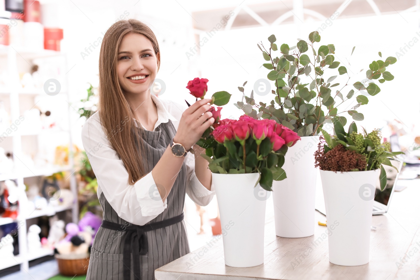 Photo of Female florist making beautiful bouquet in flower shop