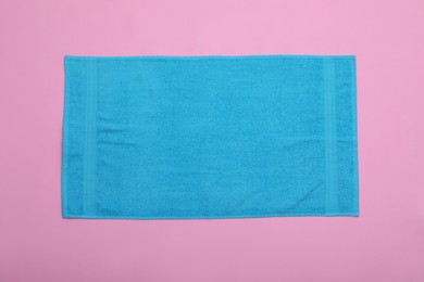 Photo of Light blue beach towel on pink background, top view