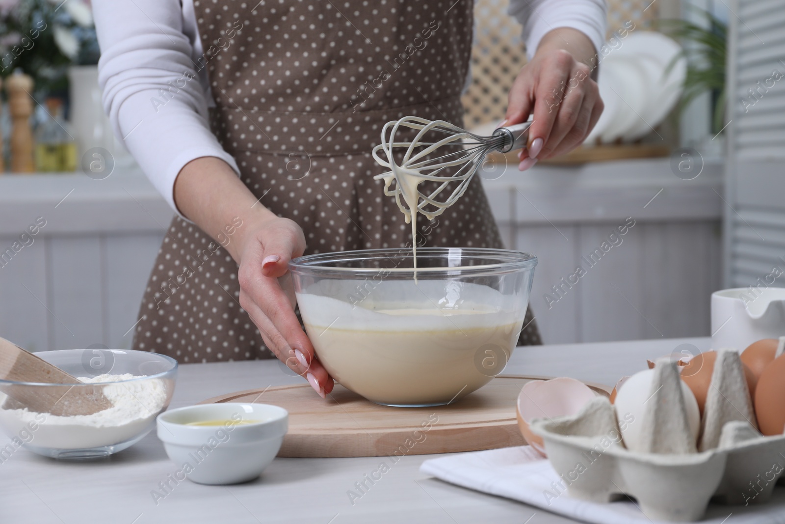 Photo of Woman making dough with whisk in bowl at table, closeup